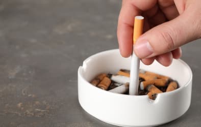 A cigarette stubbed out in an ashtray.