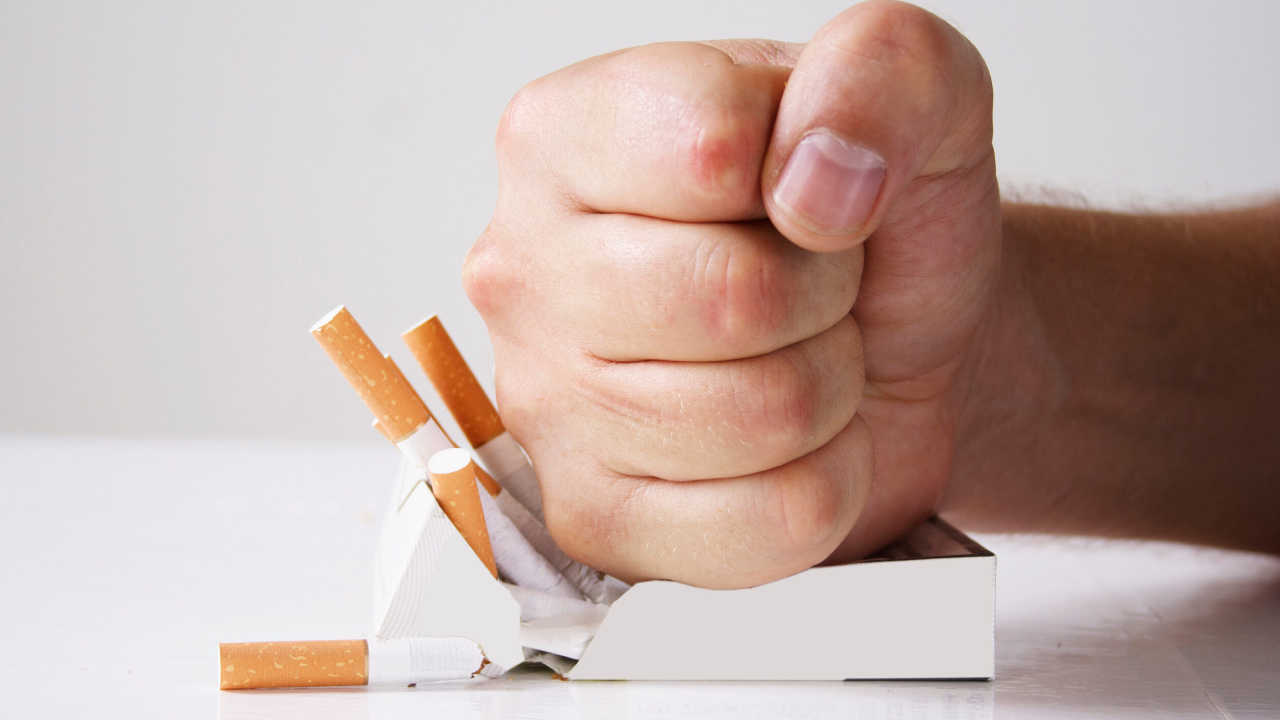 Hand crushing cigarettes over white background