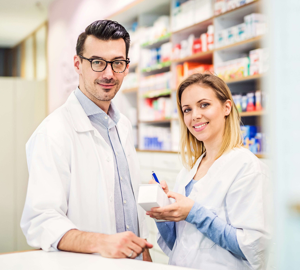 Two pharmacists in white lab coats in a pharmacy.