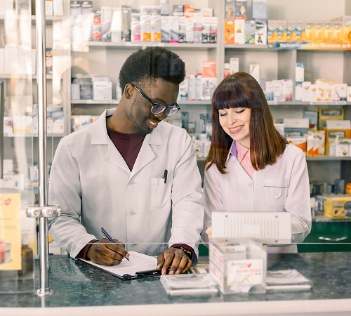 Two pharmacy staff members working together at a counter.