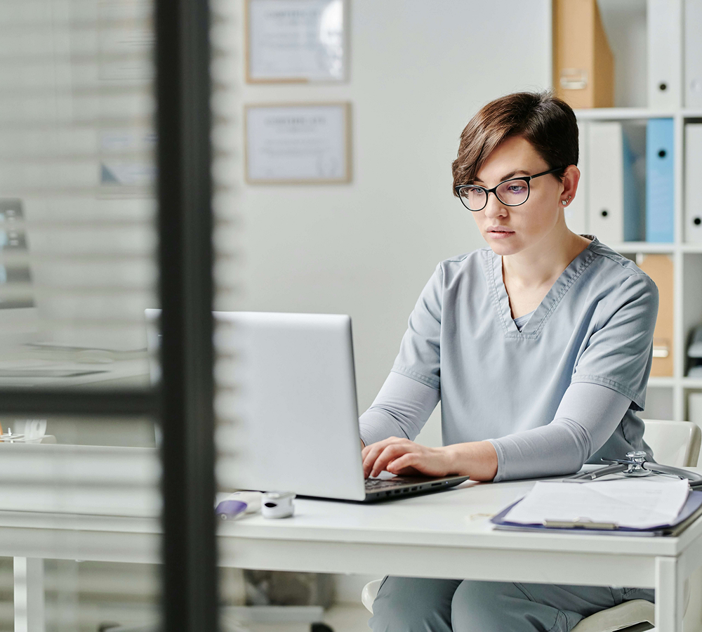 Clinician working on laptop representing healthcare technology and innovation
